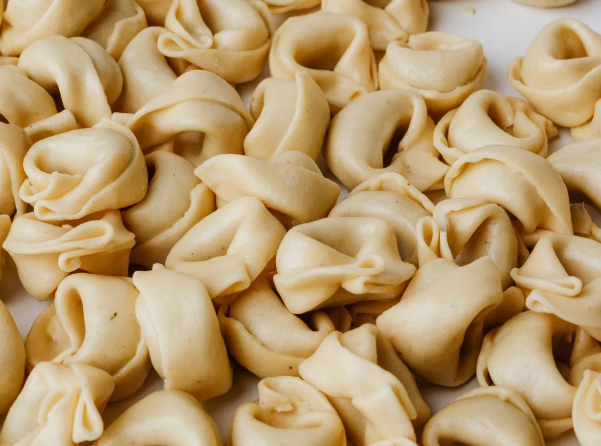 Hromada čerstvě vyrobených tortellini na světlém povrchu